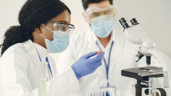 Scientists examining a sample in a pharmaceutical lab with a microscope in the foreground, good laboratory practices glp compliance principles of good laboratory practice glp in pharma glp vs gmp glp meaning in pharma what is glp in pharma glp data integrity | Scilife