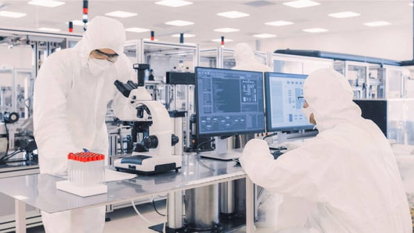 One scientist looking at data on a computer screen and another scientist looking through a microscope | Scilife