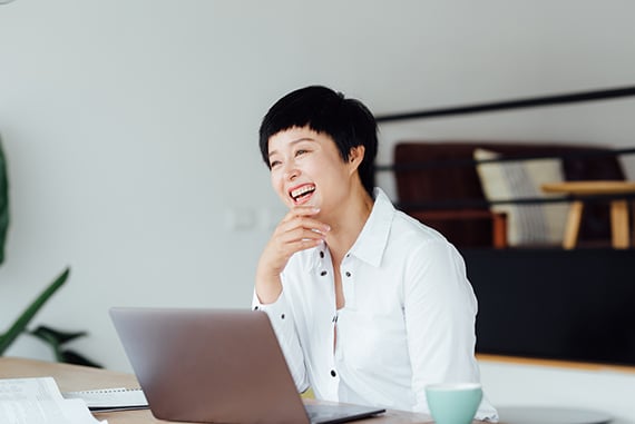 Asian woman smiling and using laptop as a image of Scilife's customers.