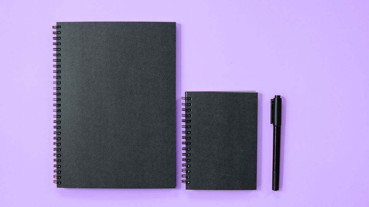 Notebooks and a pen over a purple background to represent the concept of study for our Scilife Knowledge Base